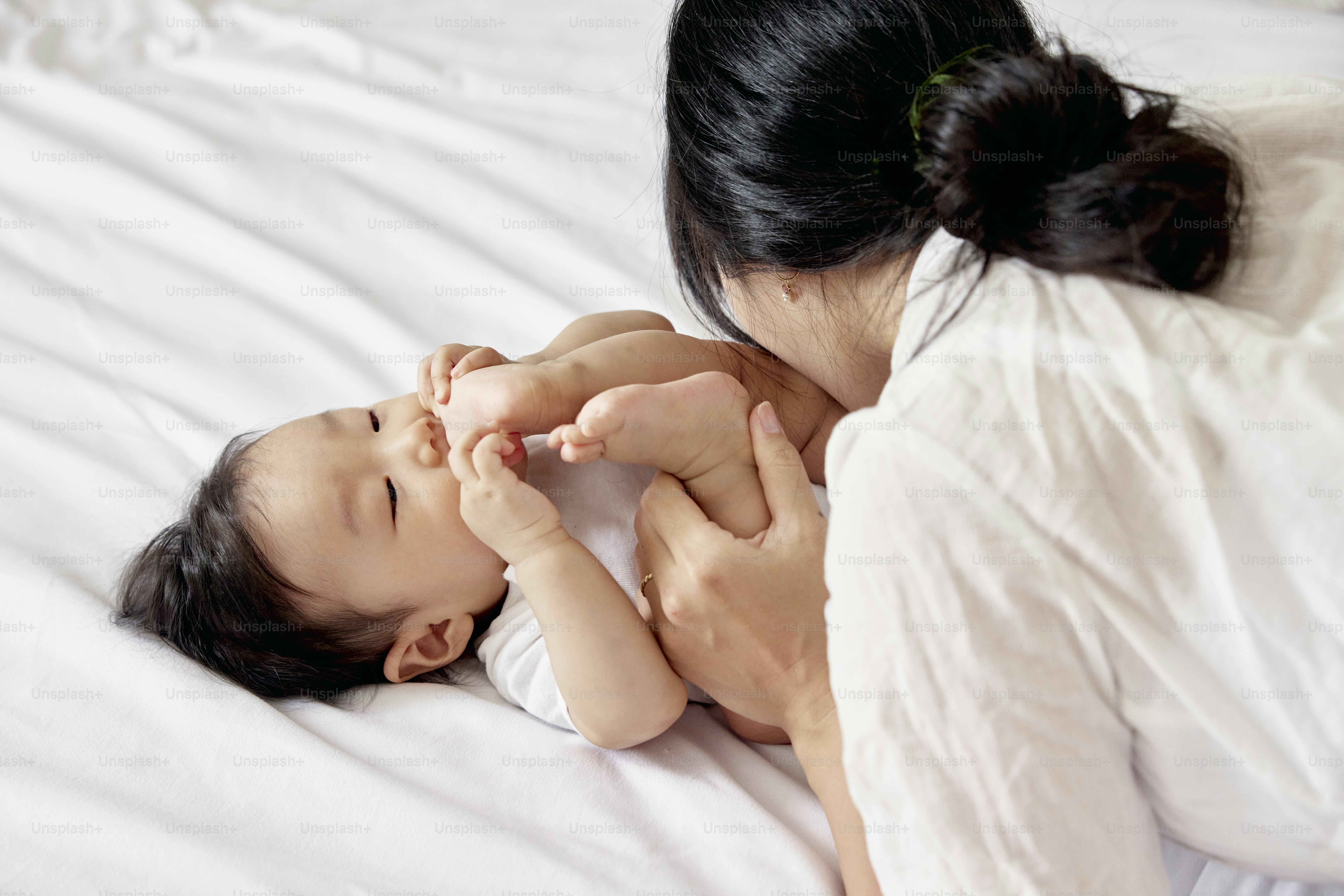 a woman holding a baby on top of a bed