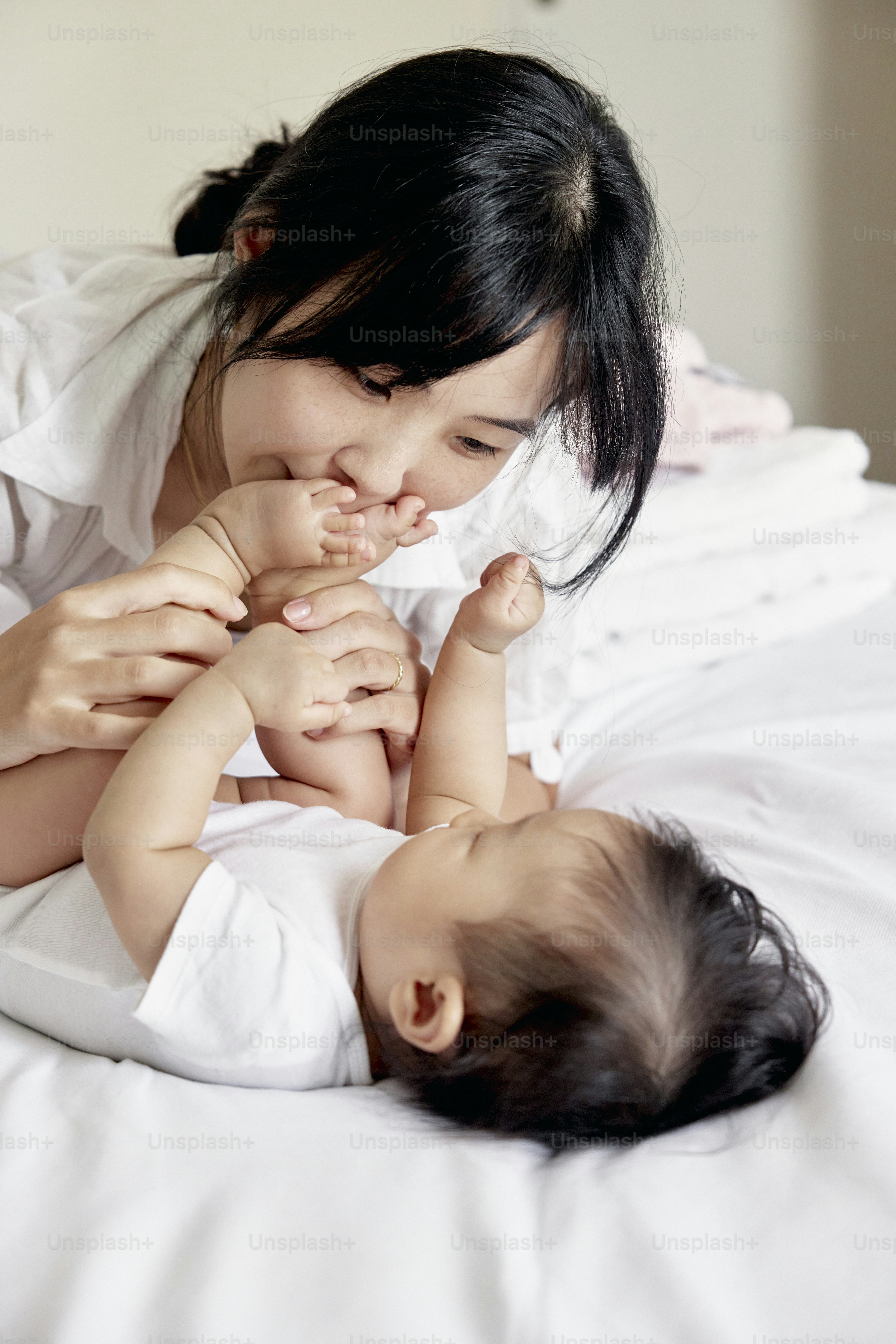 a woman laying on top of a bed holding a baby