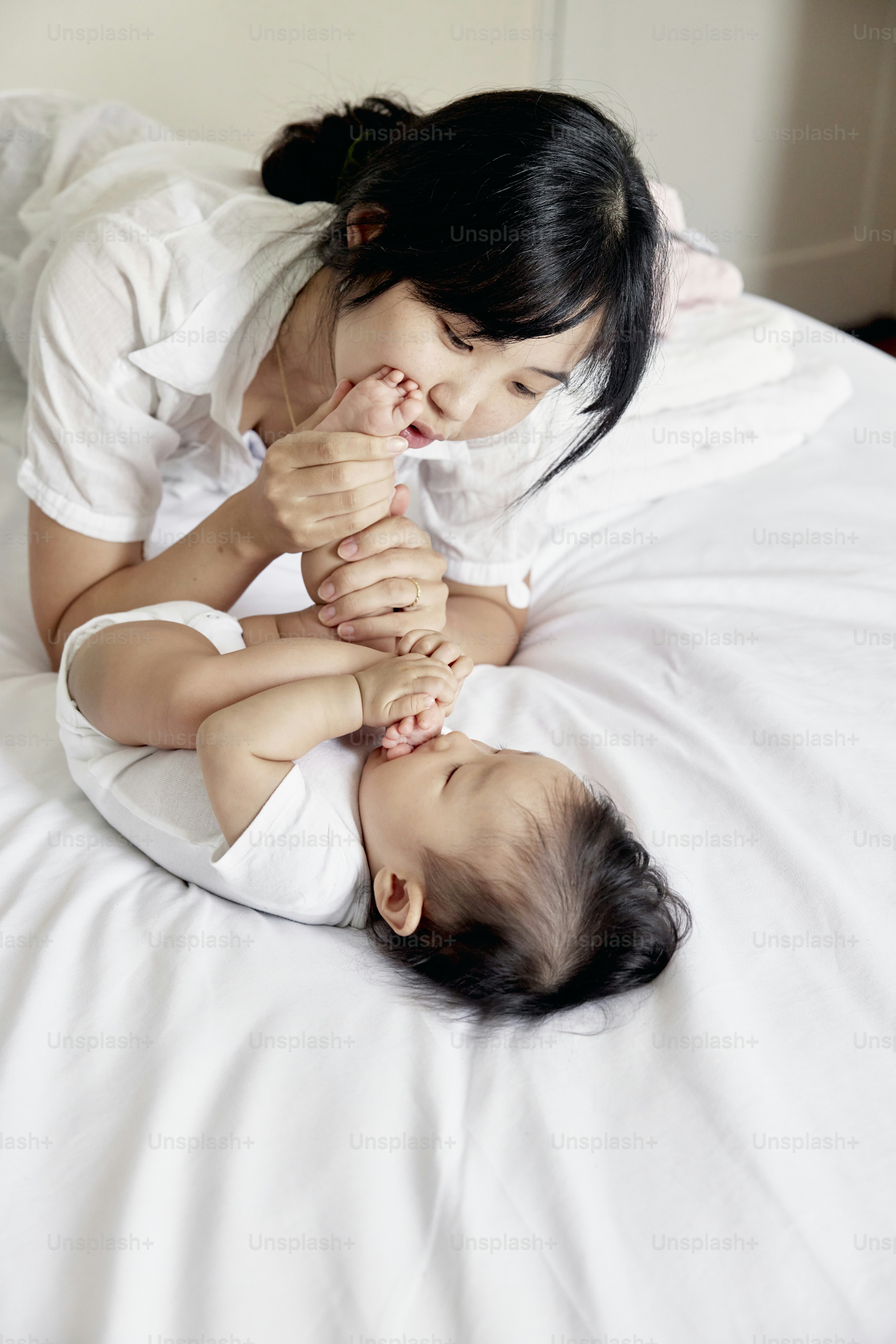 a woman laying on top of a bed next to a baby