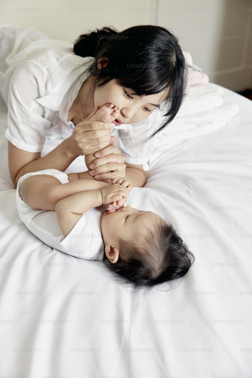Una mujer acostada encima de una cama junto a un bebé