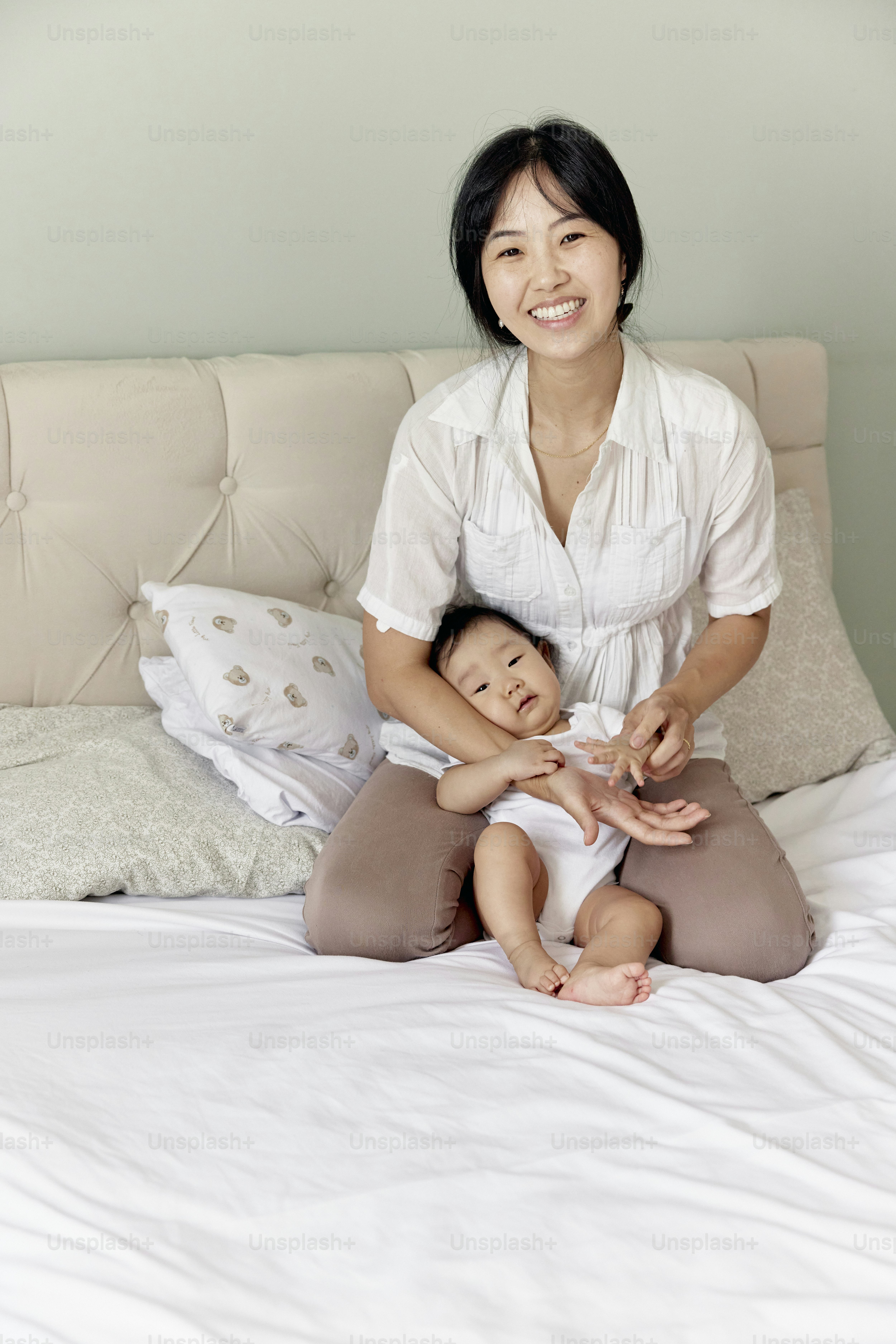 une femme assise sur un lit tenant un bébé