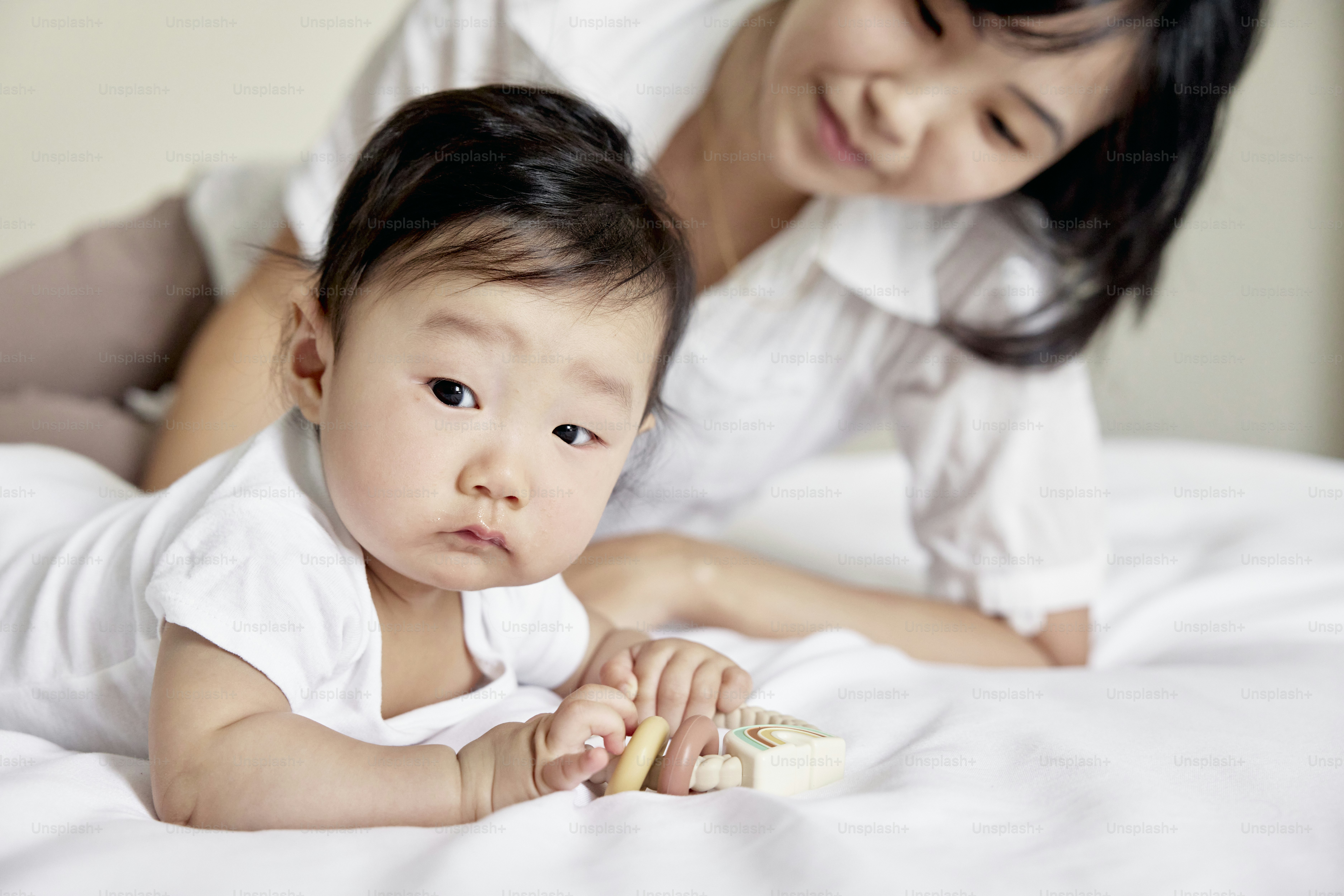 a woman holding a baby on top of a bed