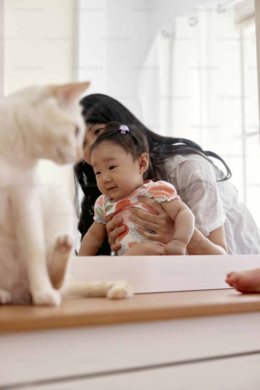 a woman holding a baby next to a cat