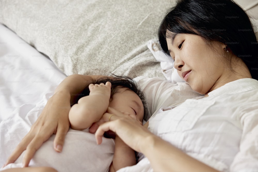a woman laying in bed next to a baby