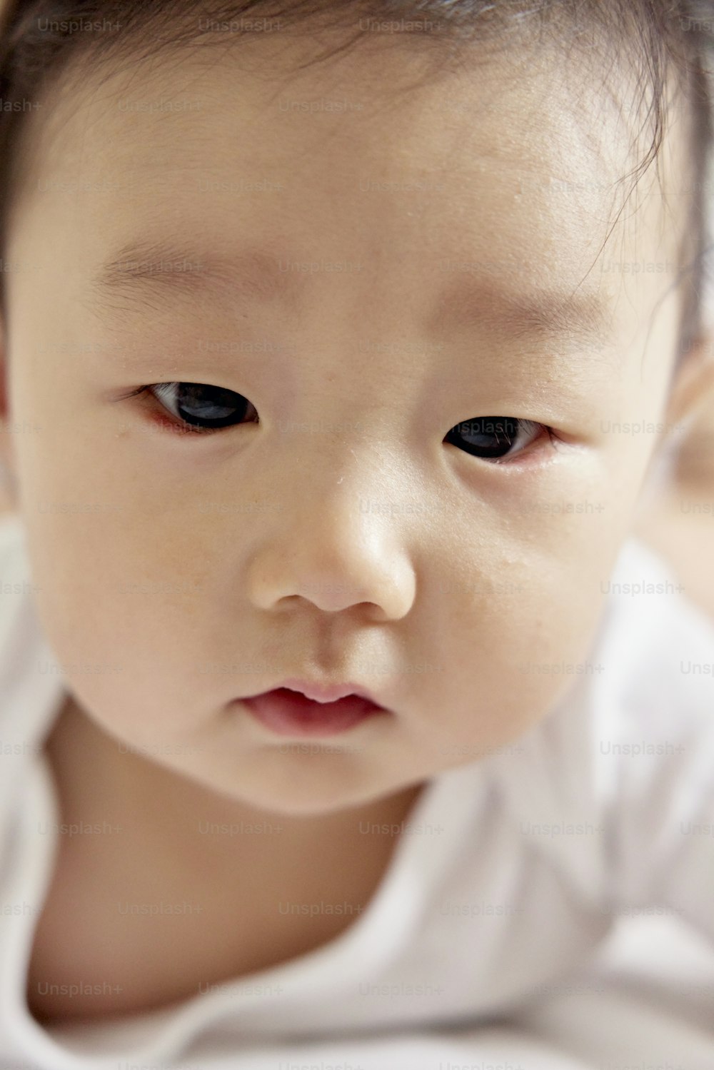 a close up of a baby wearing a white shirt