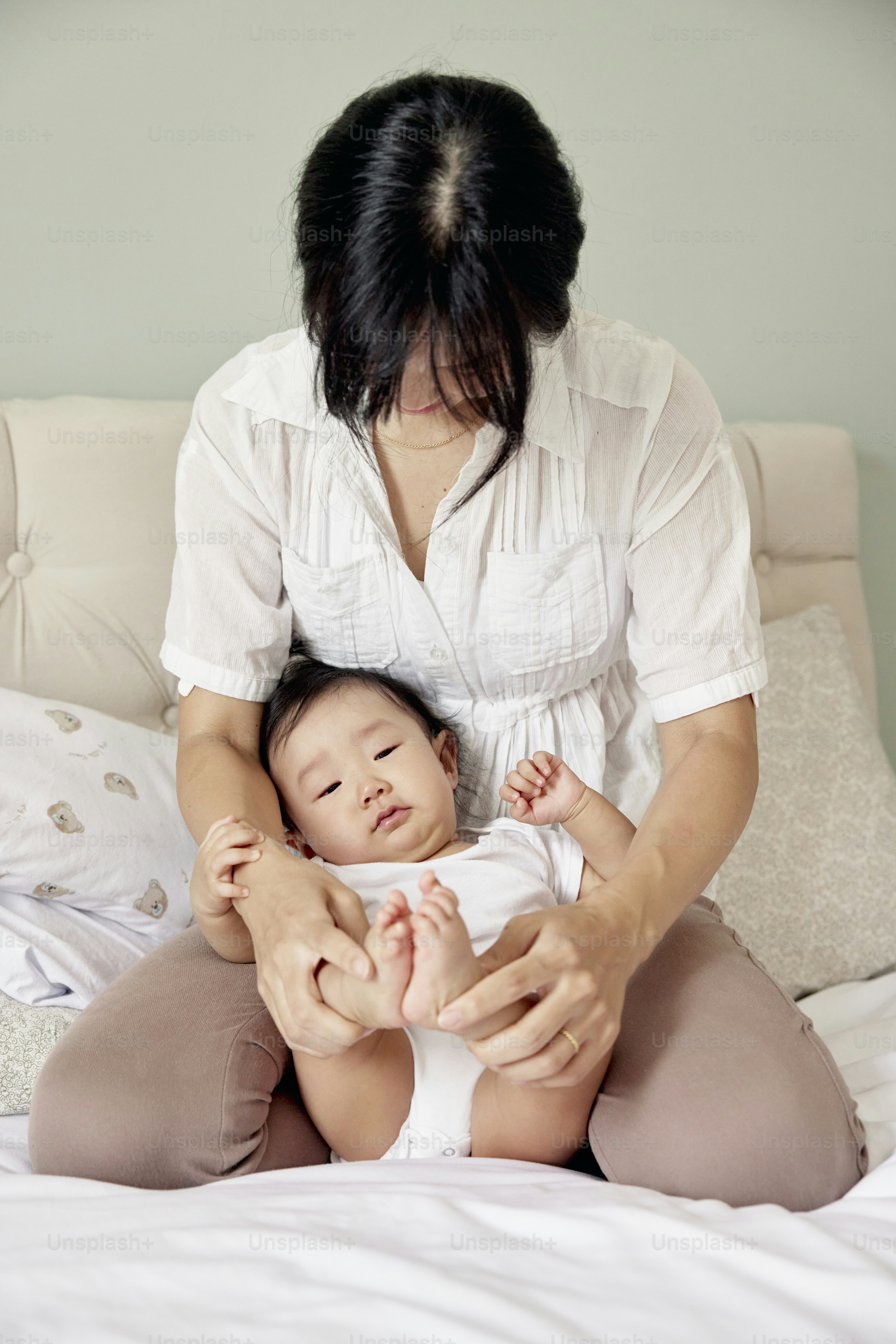 une femme assise sur un lit tenant un bébé