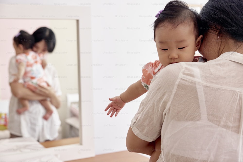 a woman holding a baby in front of a mirror