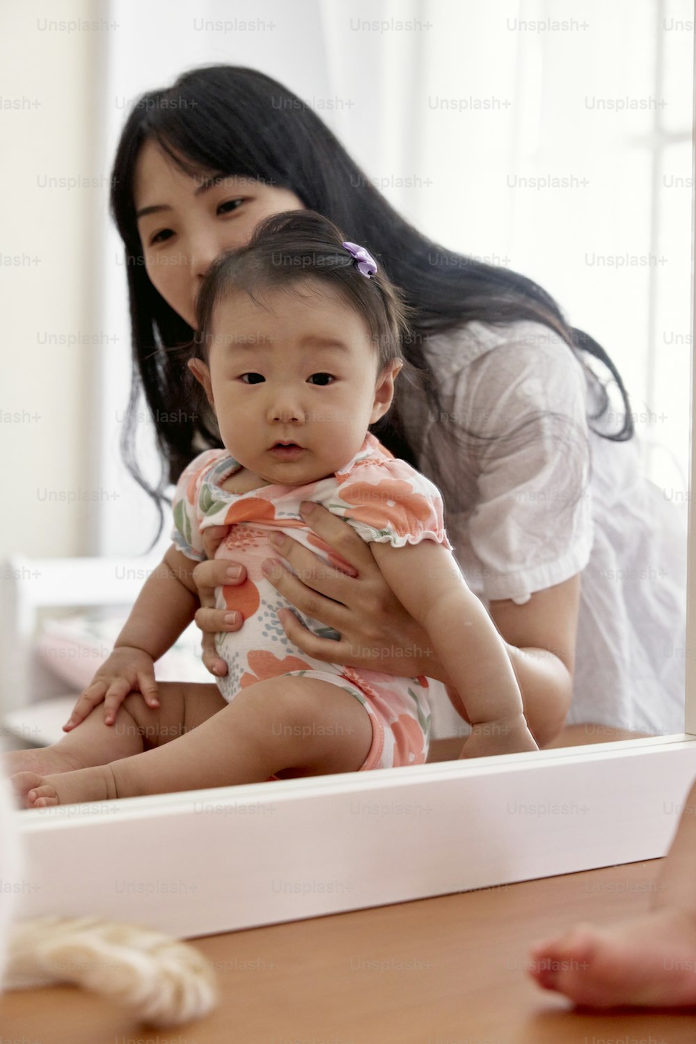 a woman holding a baby in front of a mirror