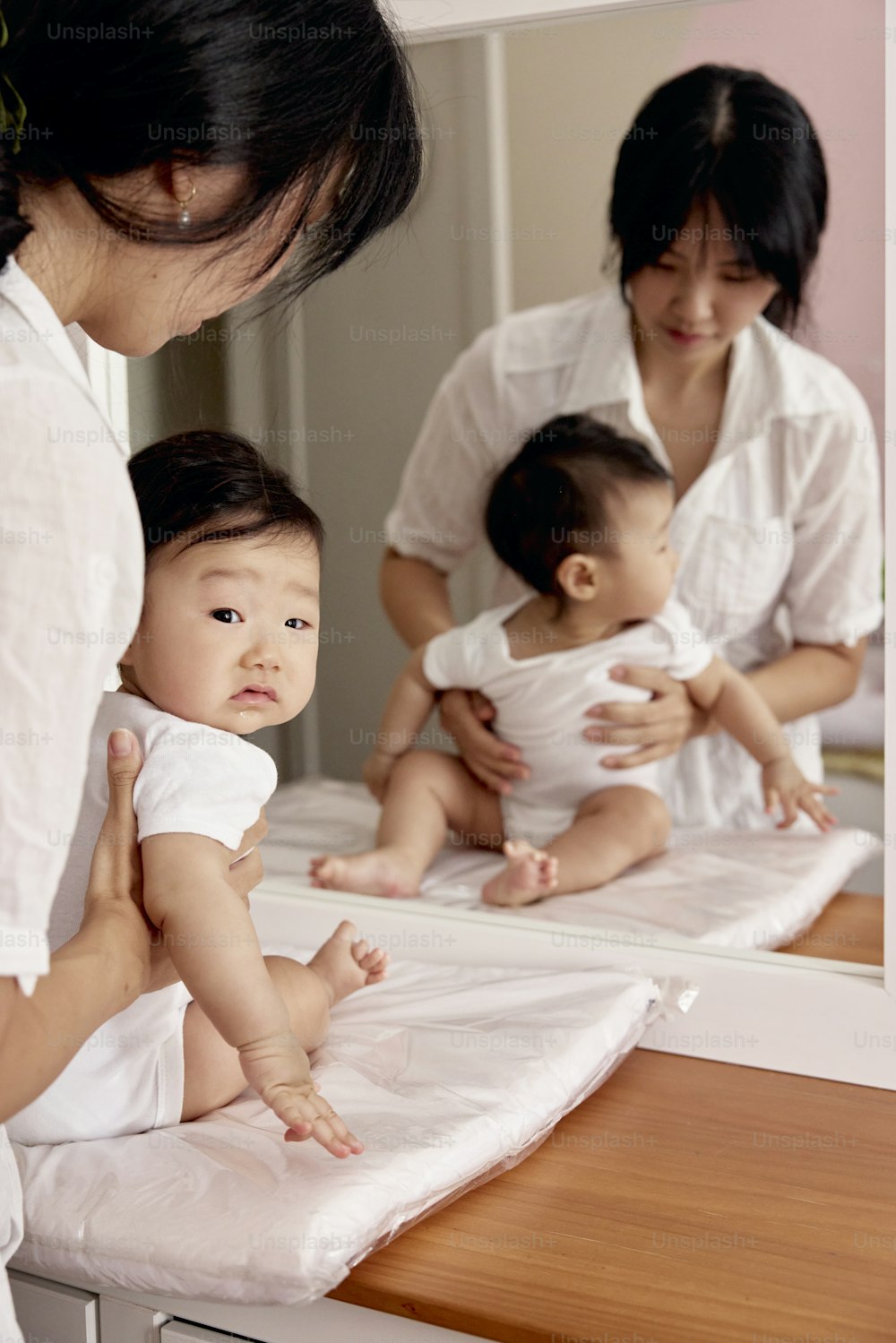 a woman holding a baby in front of a mirror