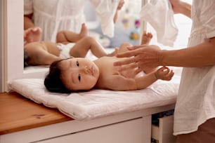 a baby laying on a bed being examined by a woman