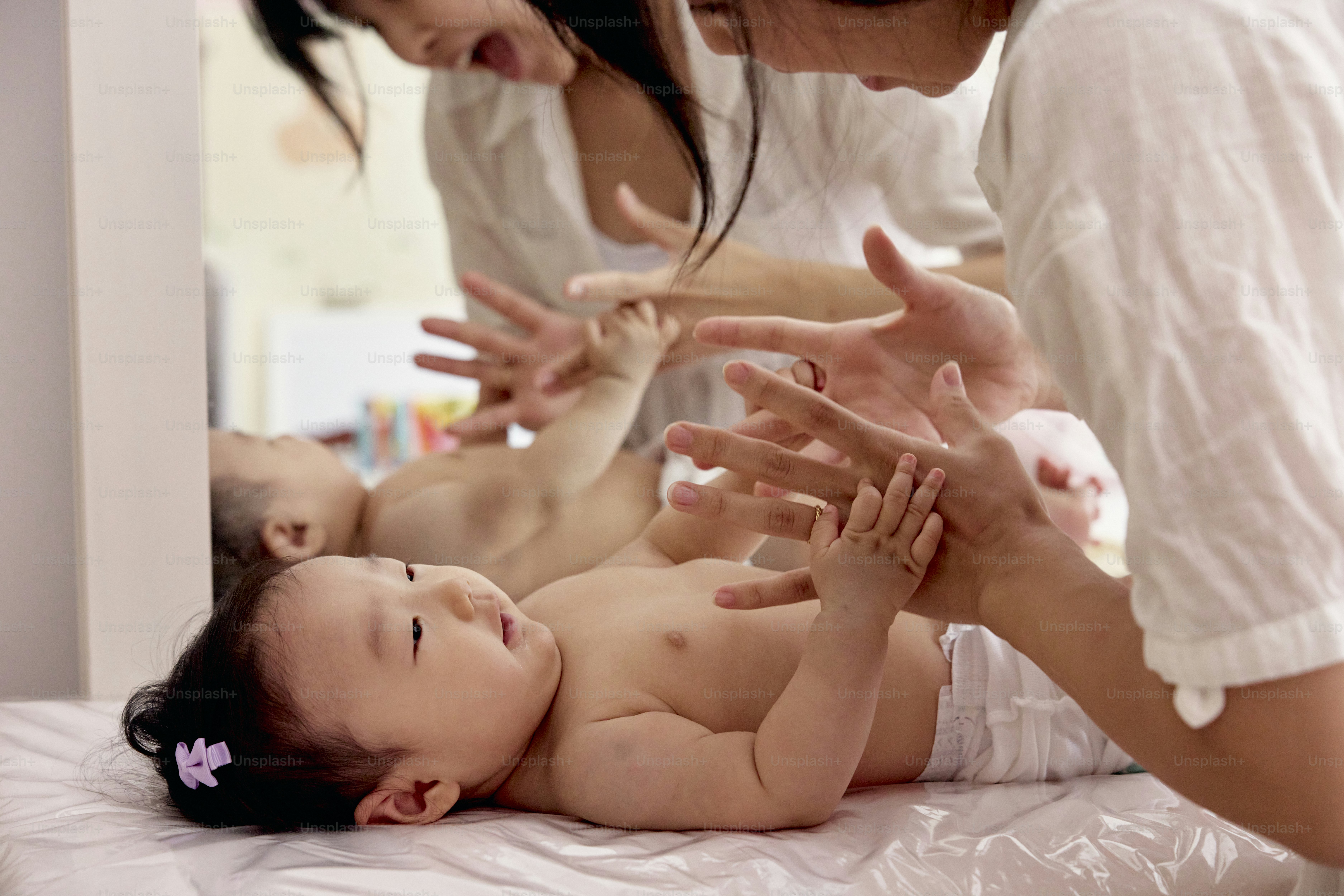 en bebis som ligger på en säng och hålls upp av en kvinna