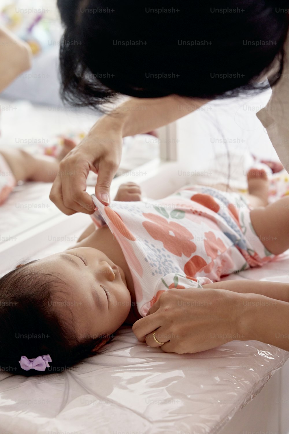 a woman combing a baby's hair while laying on a bed