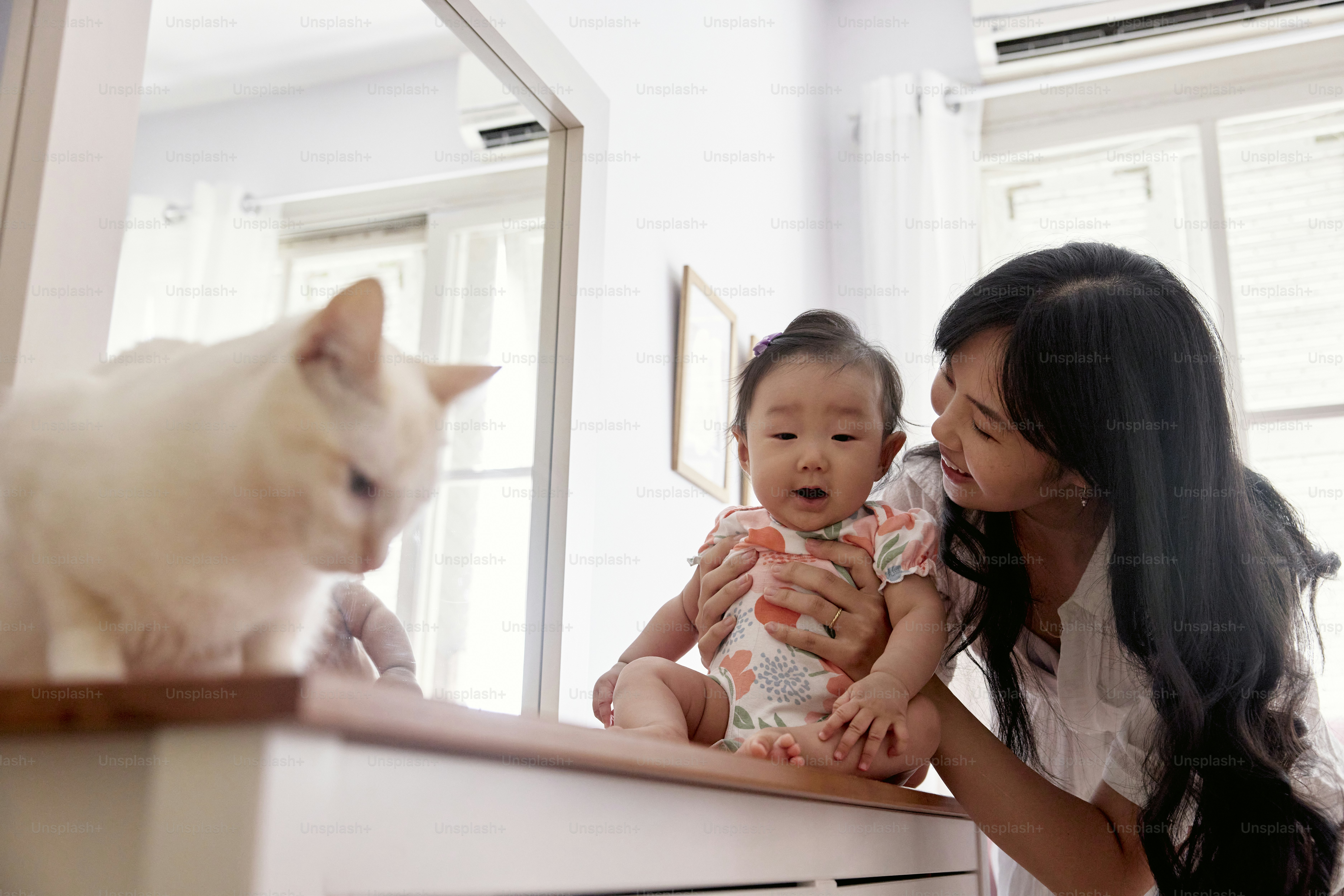 a woman holding a baby and a cat