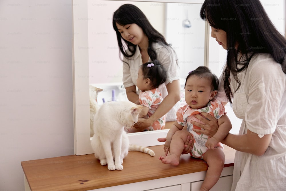 a woman is holding a baby and a cat