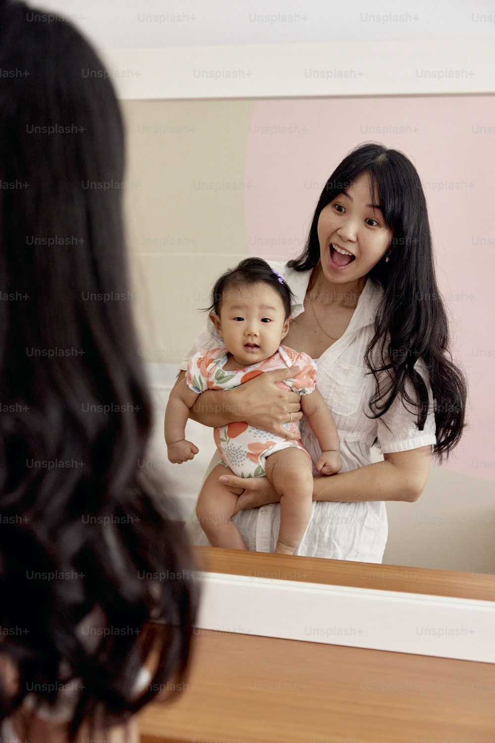 uma mulher que segura um bebê na frente de um espelho