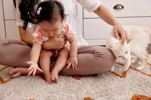 a little girl sitting on the floor next to a cat