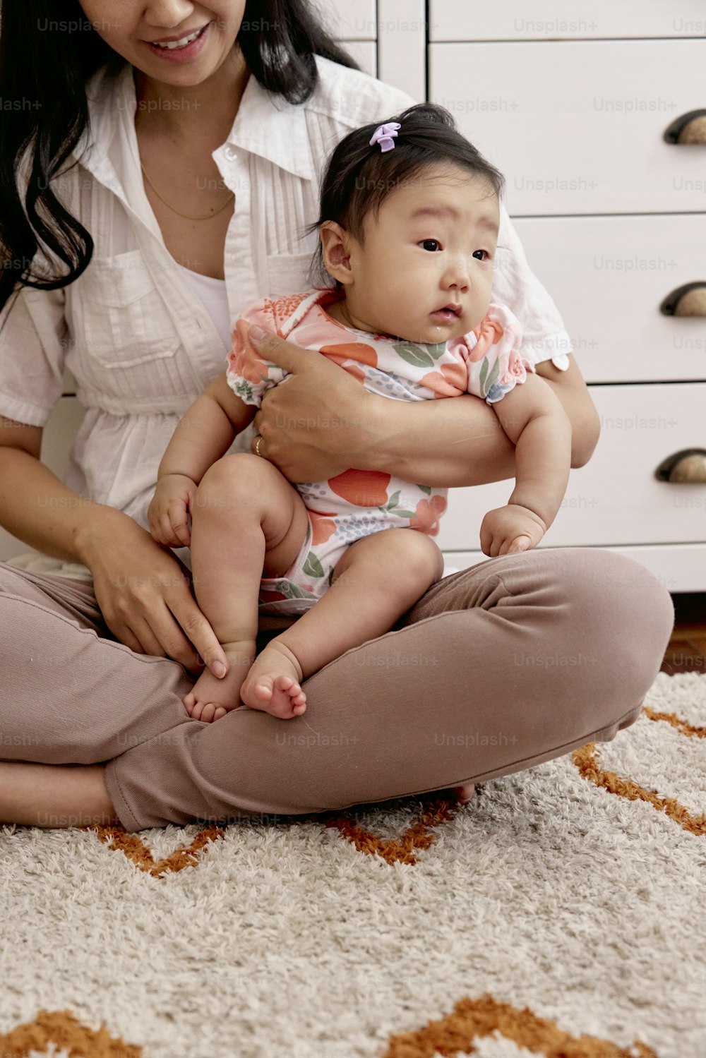 una donna seduta sul pavimento che tiene in braccio un bambino