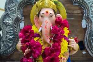 a statue of an elephant with flowers around its neck