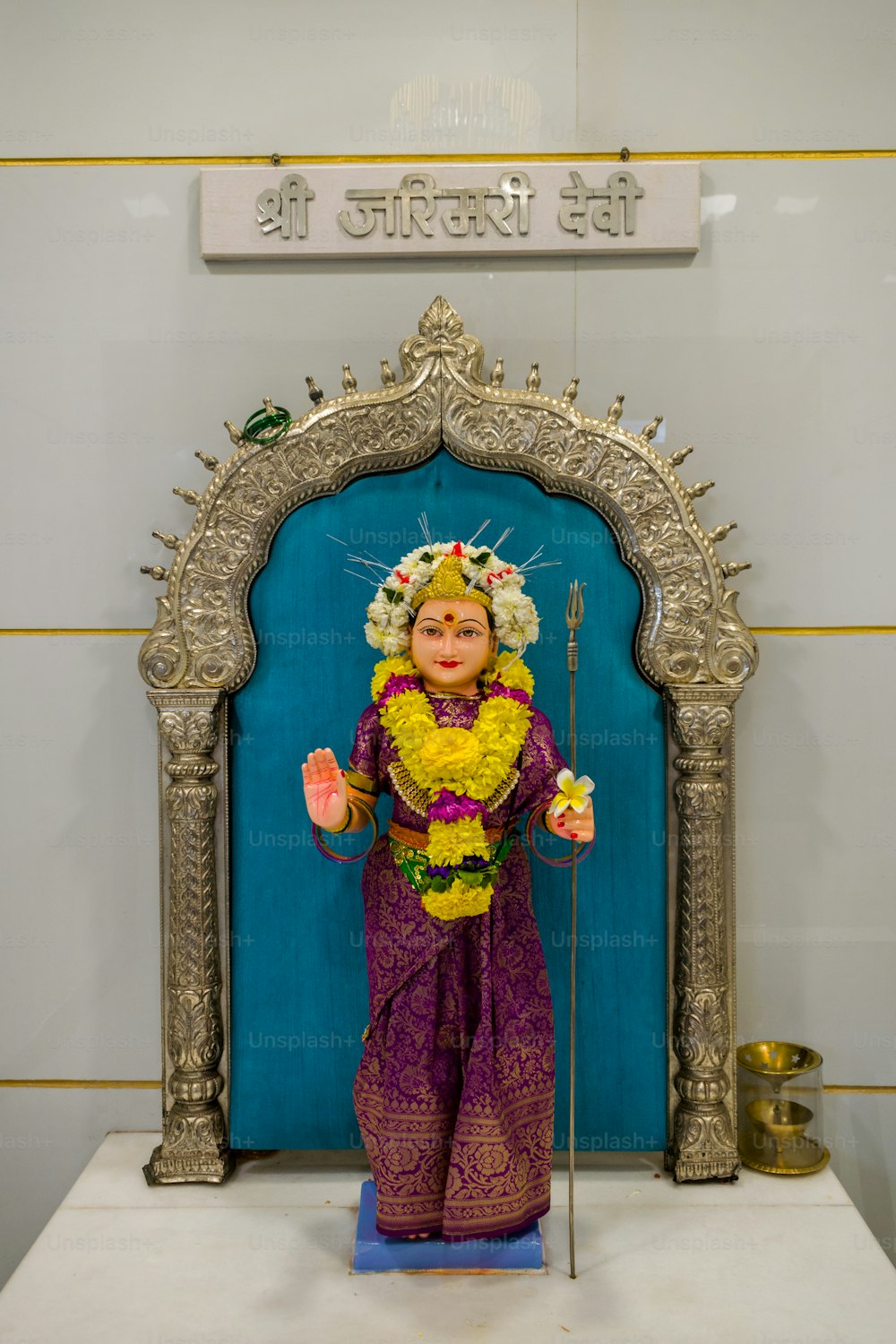uma estátua de uma mulher segurando uma flor na frente de uma porta azul
