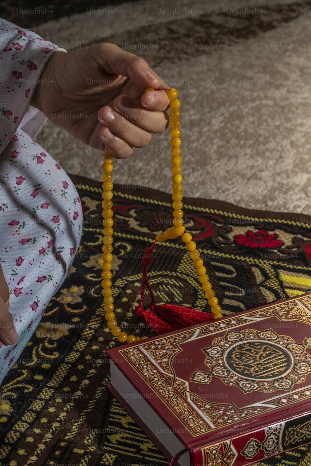 a person holding a beaded rosary next to a book