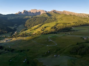 an aerial view of a green valley with mountains in the background