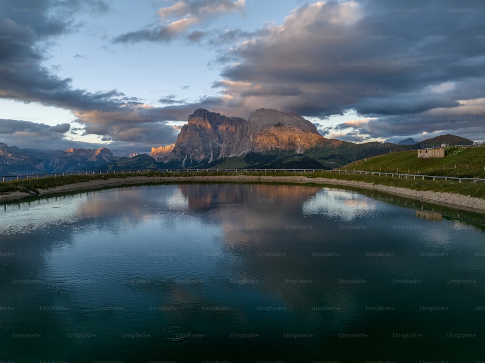 a body of water surrounded by mountains under a cloudy sky