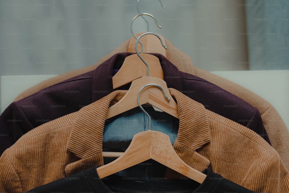a brown jacket hanging on a hanger next to a black shirt
