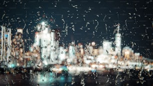 une vue d’une ville la nuit à travers une fenêtre couverte de pluie