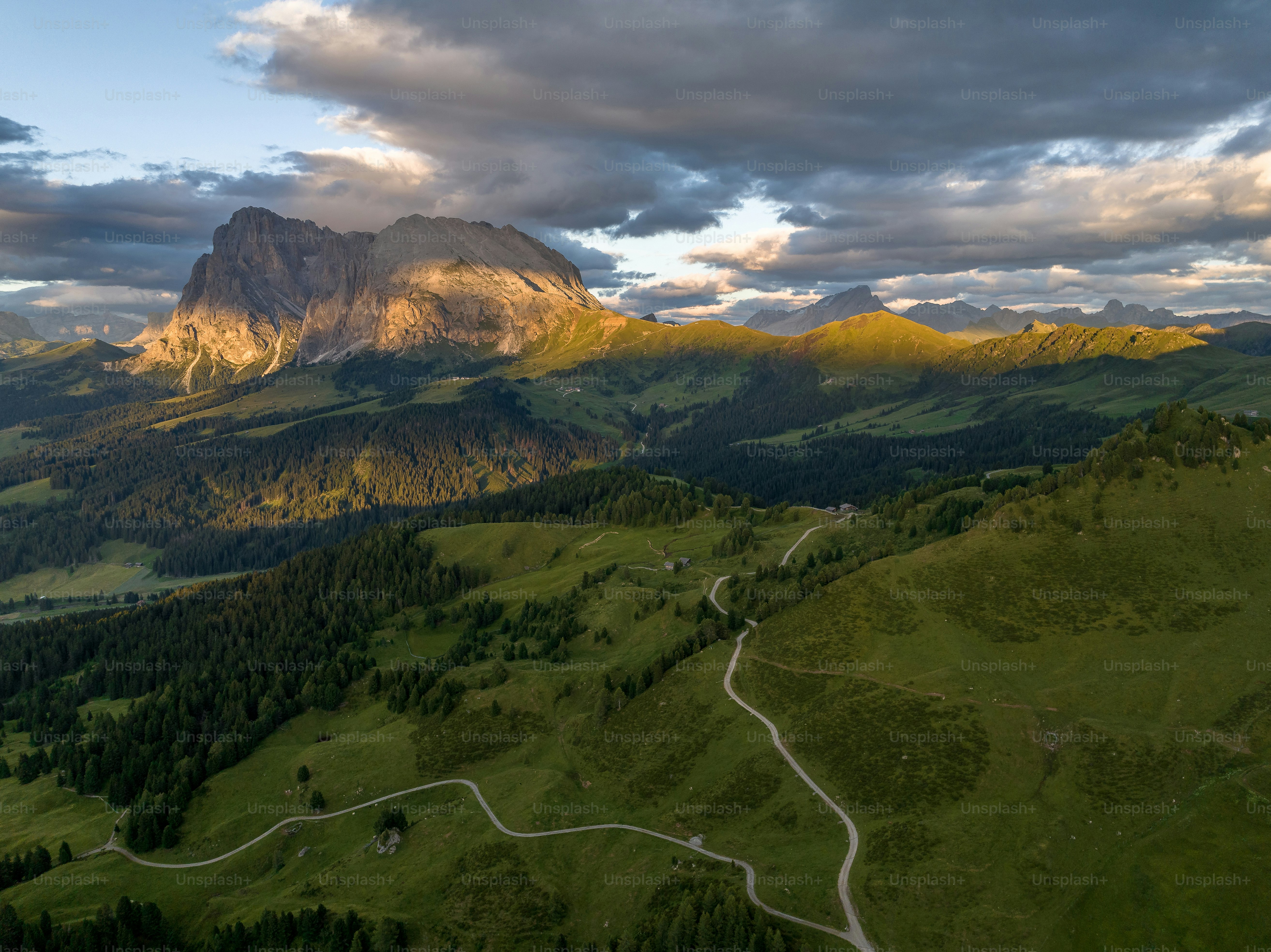 Una vista panoramica di una catena montuosa con una strada tortuosa in primo piano