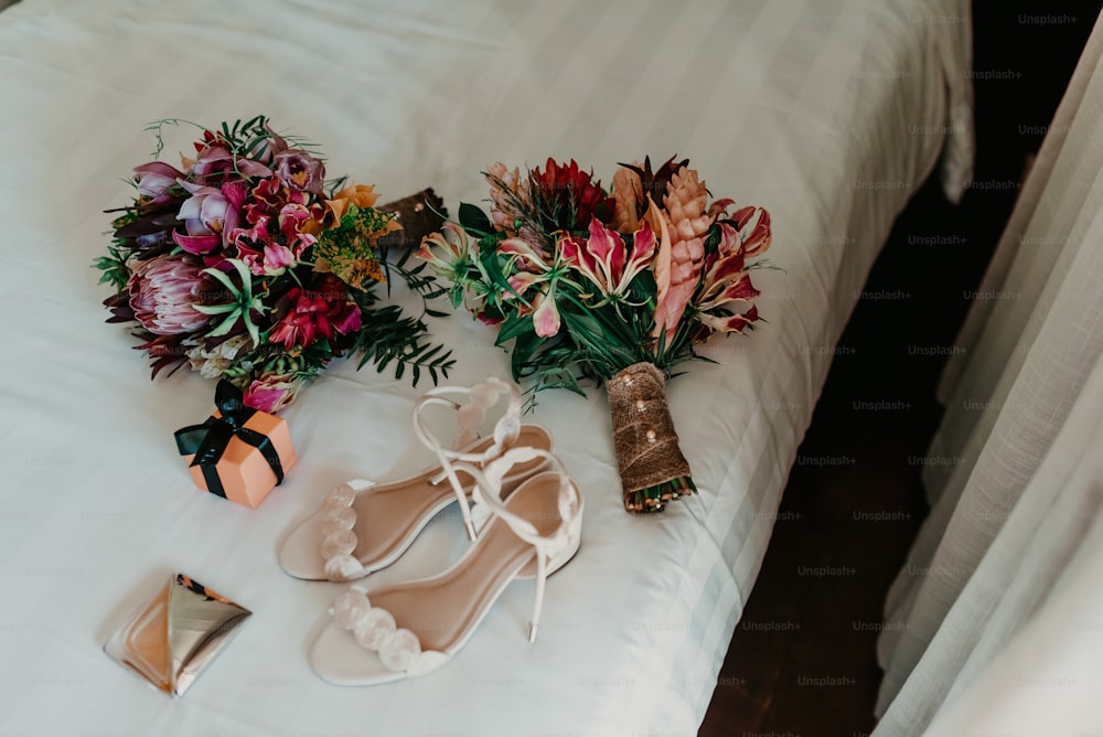 um par de sapatos e um buquê de flores em uma cama