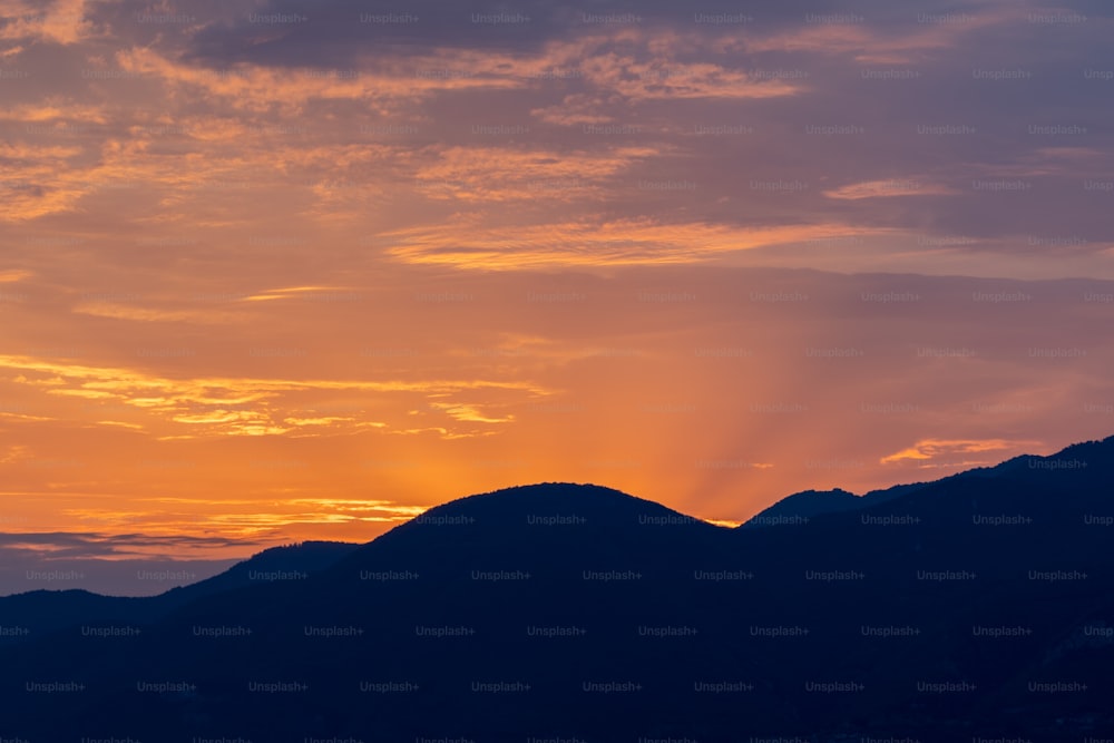 the sun is setting over a mountain range