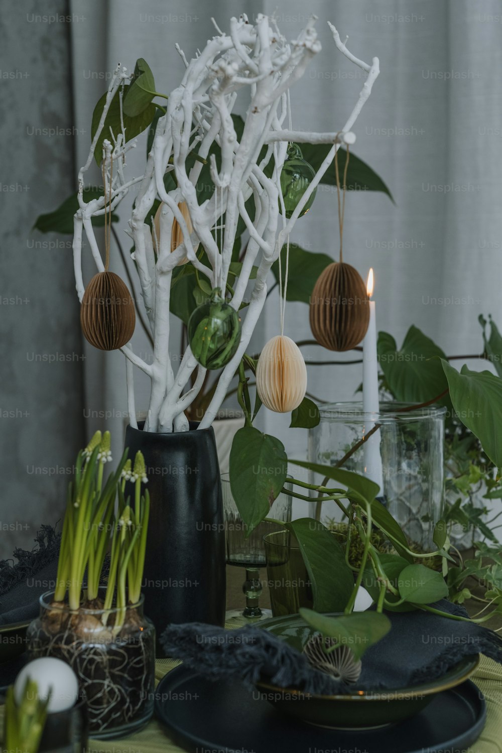 a table topped with plates and vases filled with plants