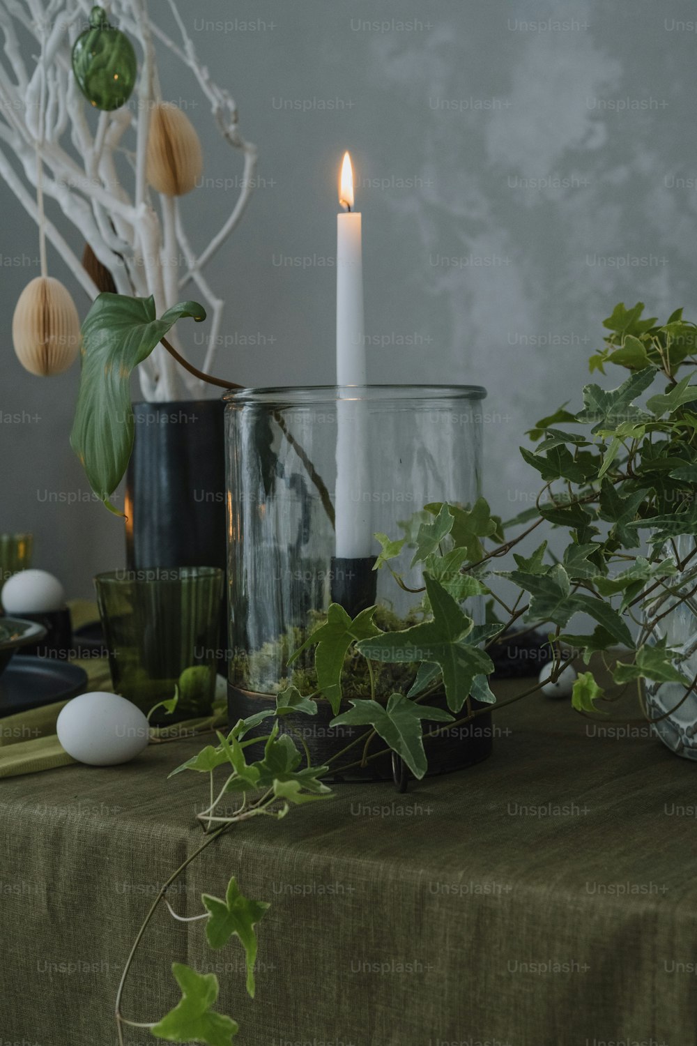 una mesa cubierta con plantas y una vela encendida
