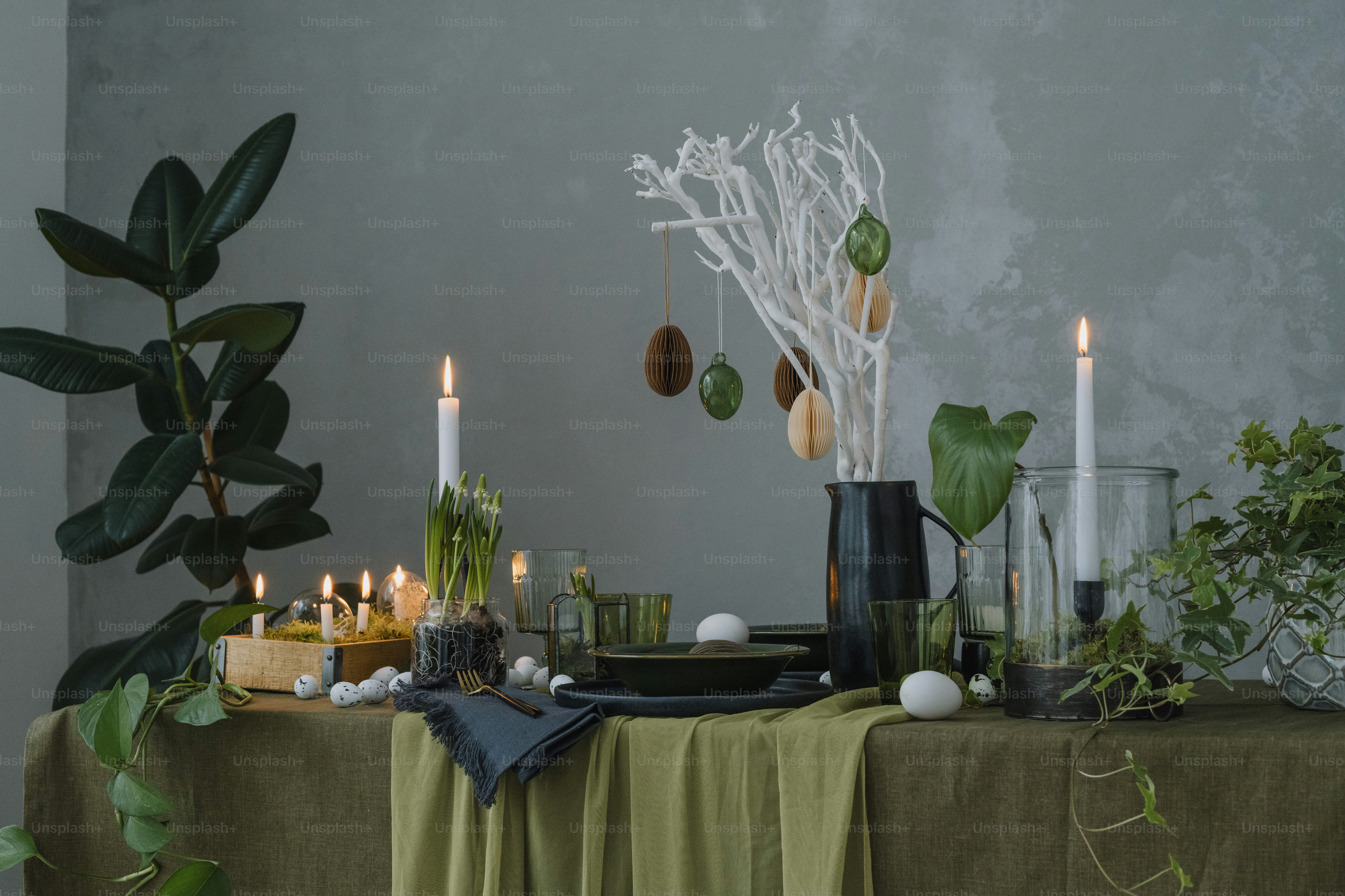 a table topped with candles and plants next to a wall