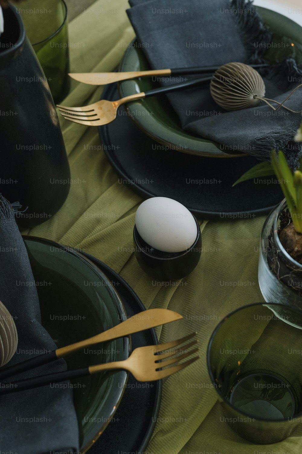 a table topped with plates and utensils next to an egg