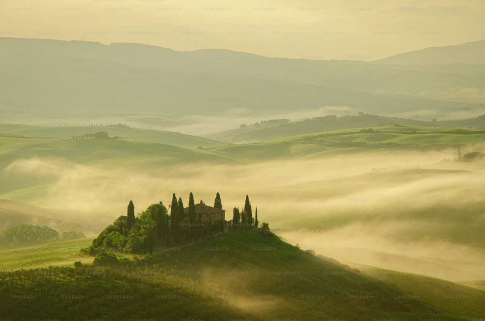 a foggy landscape with a house on a hill