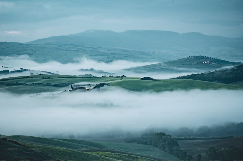 a foggy valley with rolling hills in the distance