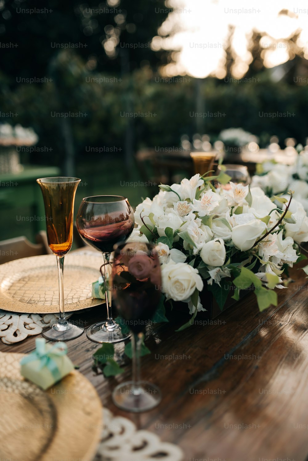 a wooden table topped with glasses of wine and flowers