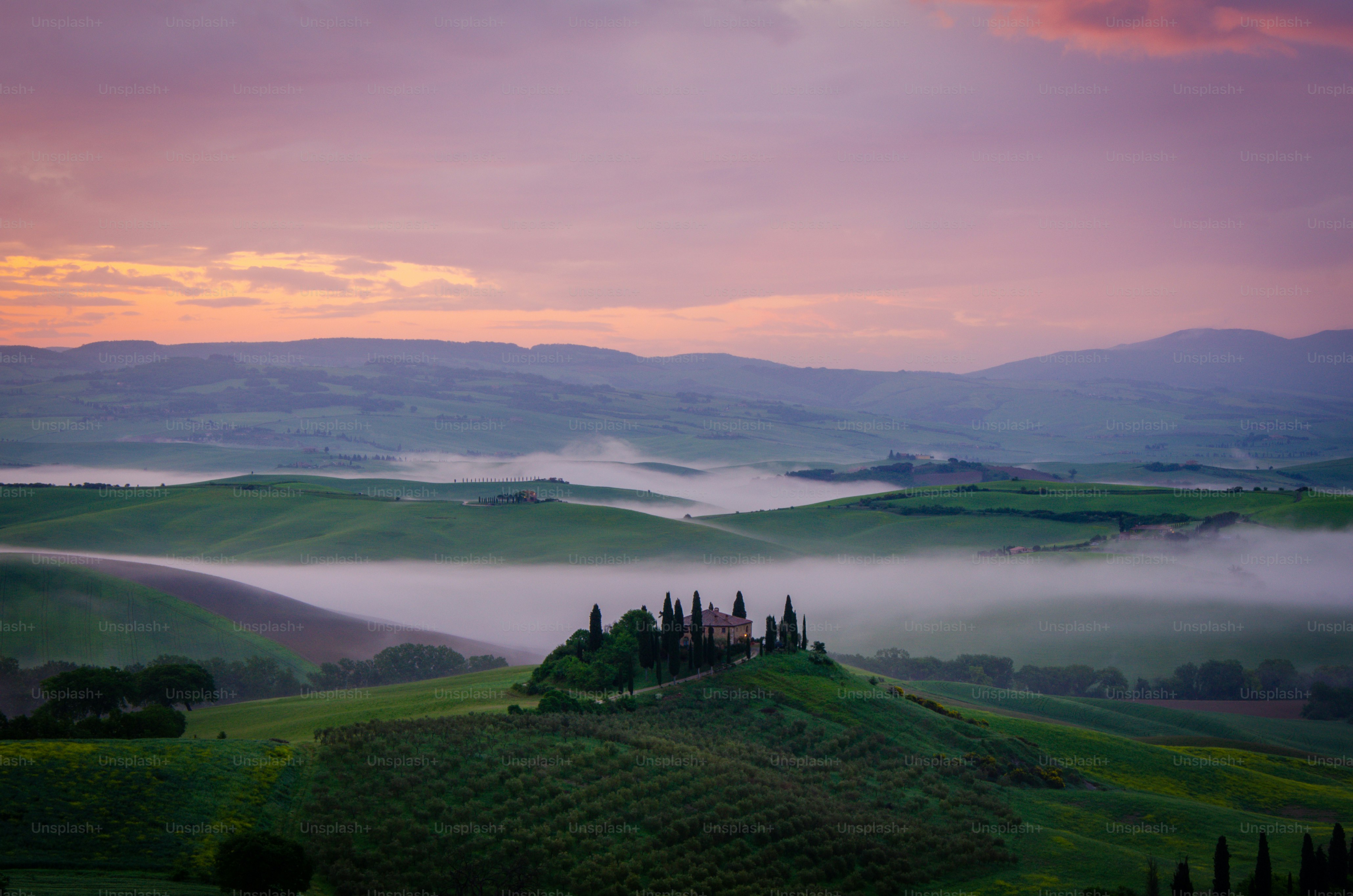 a foggy landscape with rolling hills and a castle in the distance