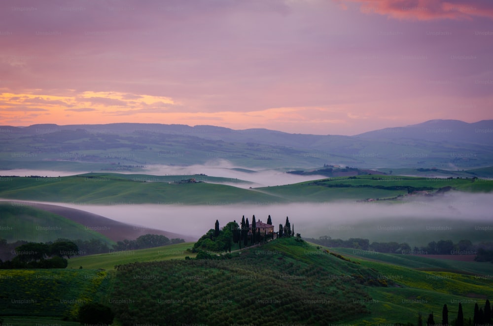 a foggy landscape with rolling hills and a castle in the distance