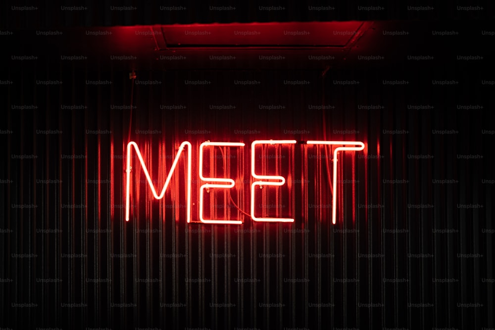 a neon sign that reads meet on a wall