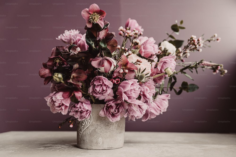 Un jarrón lleno de muchas flores rosadas