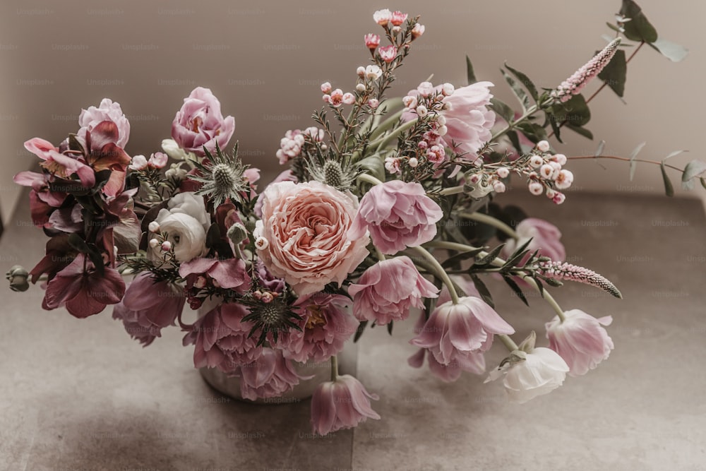 Un vase rempli de nombreuses fleurs roses et blanches
