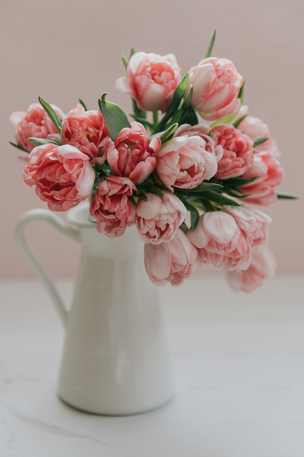 테이블 위에 분홍색 꽃으로 가득 찬 흰색 꽃병