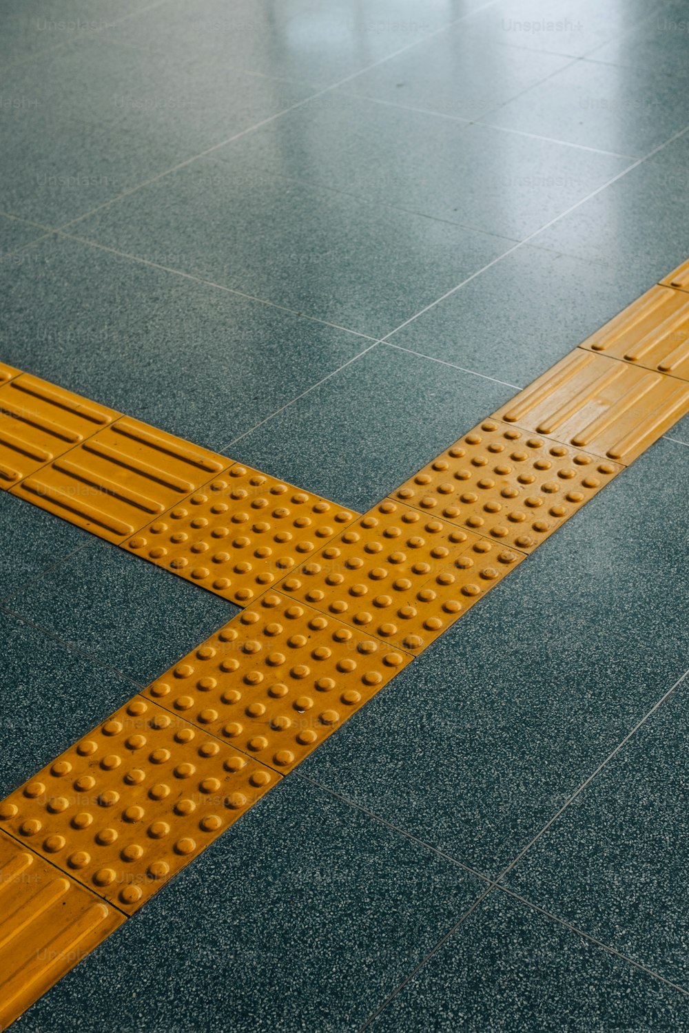 a close up of a yellow cross walk on a tiled floor