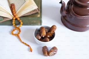 a bowl of dates next to a book and a teapot