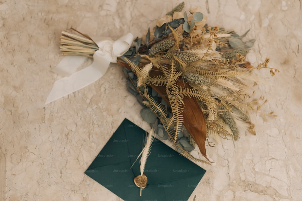 ein Strauß getrockneter Blumen und ein grüner Umschlag