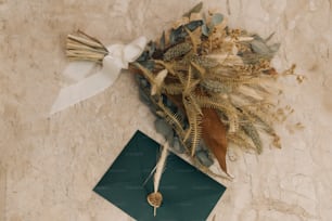 um buquê de flores secas e um envelope verde