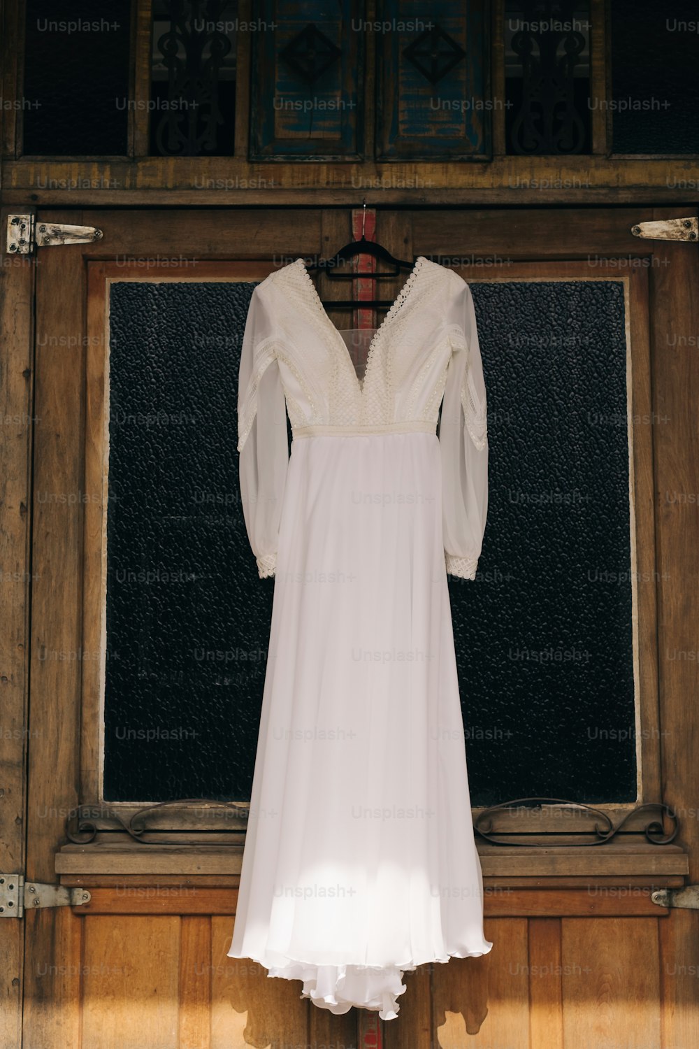 um vestido branco pendurado em uma parede de madeira