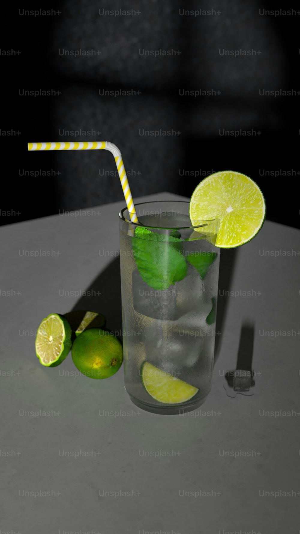 a glass with a straw and limes on a table